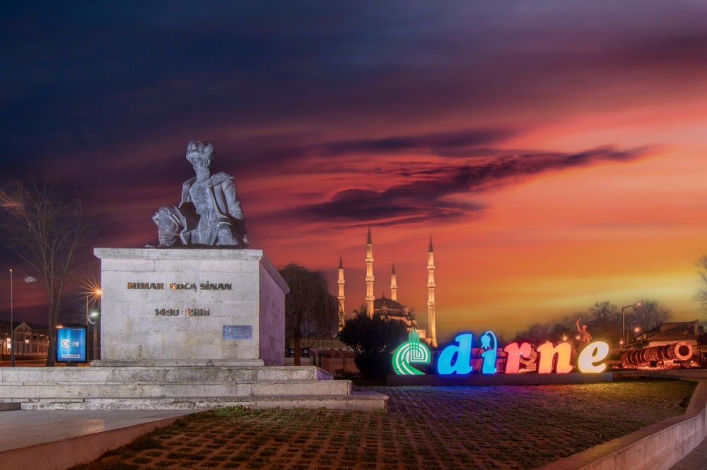 Selimiye Camii aksam isiginda — silueti alacakaranlik gokyuzune karsi parlıyor, sicak yapay aydinlatma mimari detaylari vurulamaya basliyor